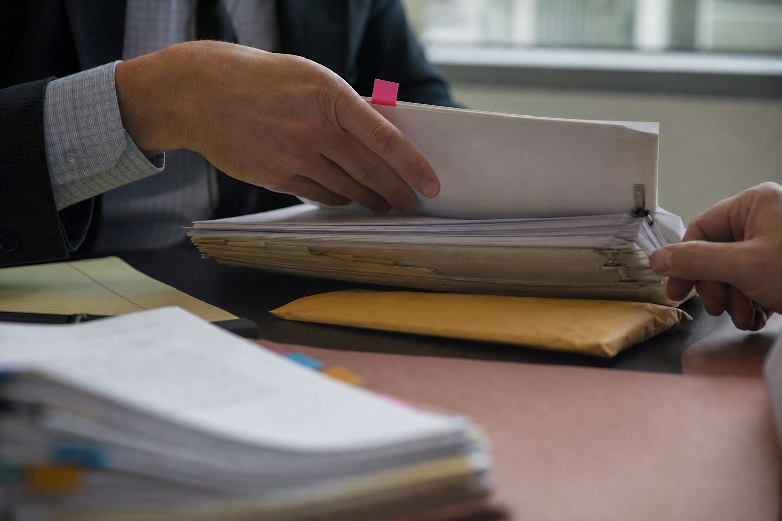 A case file thick with tabbed records changes hands across a desk.